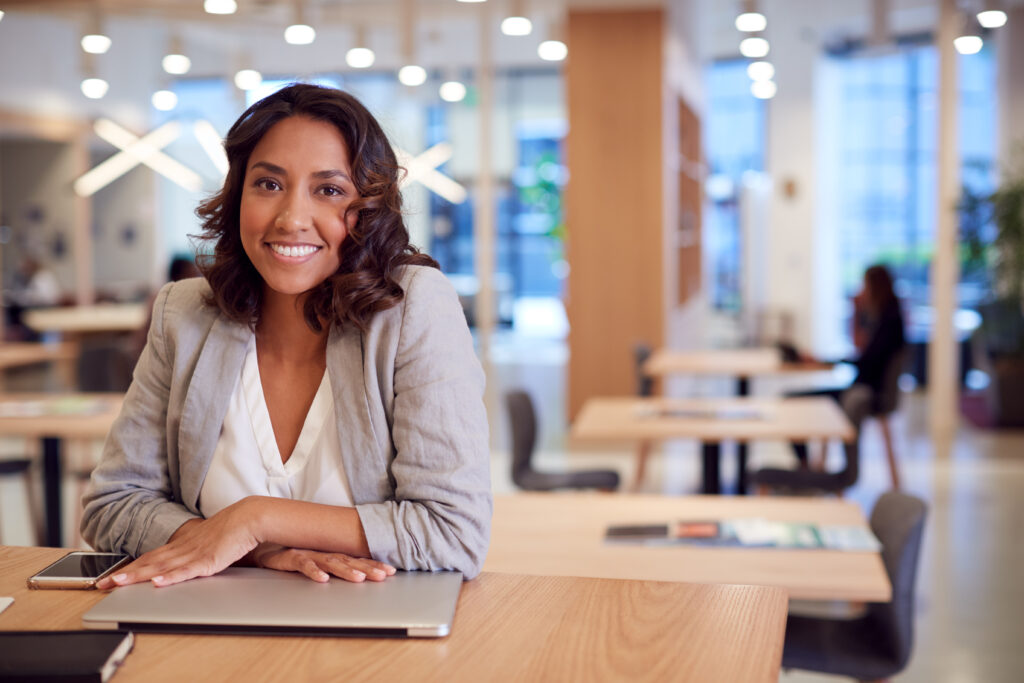 portrait of businesswoman at desk in modern office work space with closed laptop